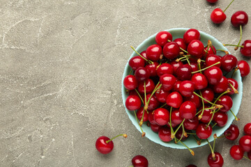Fresh sweet cherries bowl on grey background, top view