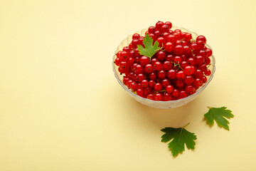 Bowl with ripe red currant on yellow background. Top view.