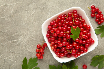 Bowl with ripe red currant on grey background. Top view.