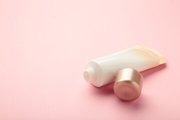 Top view blank label facial skincare tube bottle with lid open on pink background