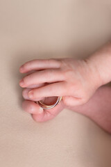 Fototapeta premium hand of a newborn with wedding rings of parents. small pens. hands on a white background. ring in a child's hand