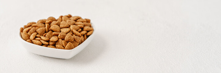 Cat food in a white bowl near the copy space, wide format for the banner