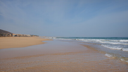 Empty and tranquil beach with golden sand and clear blue waters known locally as Playa de Costa Calma, stretching along the south-eastern coast of the island of Fuerteventura, Canary Islands, Spain