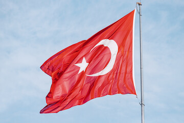 The national Turkish flag on a blue sky background. Patriotism and state power concept.