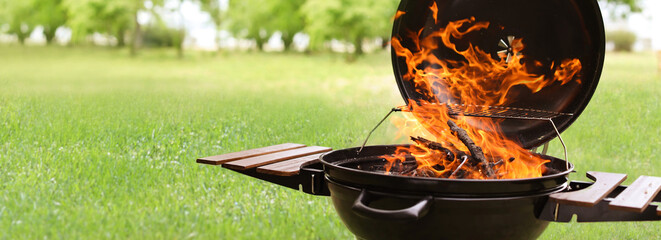 Modern barbecue grill with fire flames outdoors, space for text. Banner design