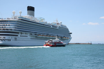 Modern cruise ship and boat in sea on sunny day
