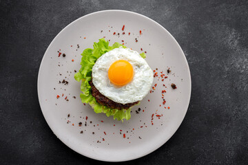 Beefsteak with egg and mashed potatoes on a dark background