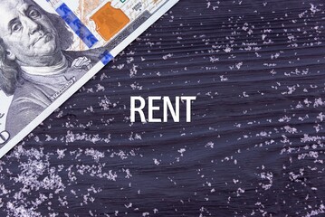 RENT - word (text) on a dark wooden background, money, dollars and snow. Business concept (copy space).
