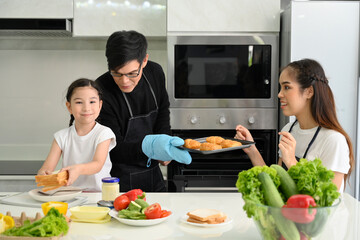 Overjoyed young family with little preschooler kids have fun cooking baking pastry at home together, happy smiling parents enjoy weekend cooking in kitchen