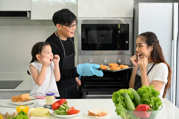 Overjoyed young family with little preschooler kids have fun cooking baking pastry at home together, happy smiling parents enjoy weekend cooking in kitchen