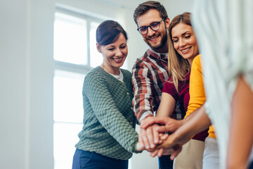 Smiling people from the group therapy, holding hands together, one over the other.