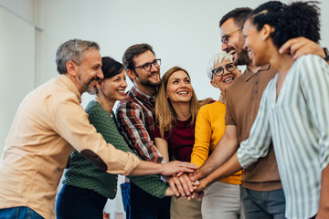A group of smiling people finished a therapy session, putting hands in the middle.