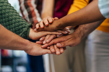 Close up of people's hands with different skin color, standing in the circle putting hands in the...
