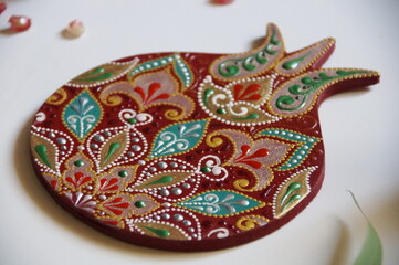 Handpainted pomegranate with intricate ornate pattern, made from wood, painted with acrylic colors. Ornamental design on a red background.