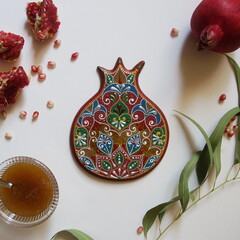 Rosh Hashanah Concept (Jewish New Year). Traditional symbols - pomegranate, honey and handmade pomegranate, made from wood, painted with acrylic colors. Top view