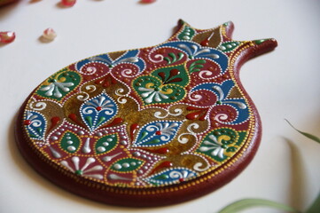 Handpainted pomegranate with intricate ornate pattern, made from wood, painted with acrylic colors. Ornamental design on a red background.