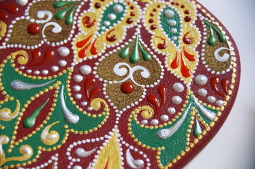 Handpainted apple with intricate ornate pattern, made from wood, painted with acrylic colors. Ornamental design on a red bakground.