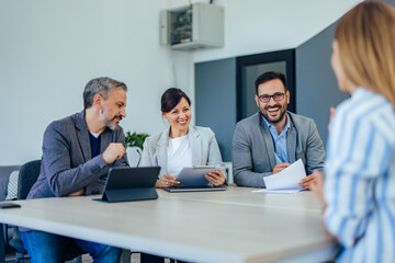Smiling business colleagues talking to each other, having a meeting.