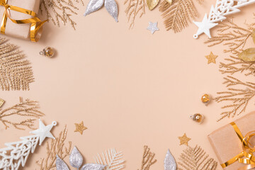 Fototapeta na wymiar Christmas festive background from twigs and leaves of golden glitter on pastel beige. Empty copy space for greeting text