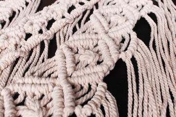 Fragment of wall decor macrame pattern on black background