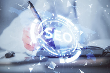 Double exposure of woman's hands making notes with SEO icon. Concept of Search engine optimization
