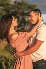 A couple of lovers man and woman hugging and kissing in a meadow at sunset.Love,passion,youth,happiness,summer concept.