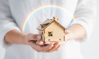 woman hands holding home model with rainbow