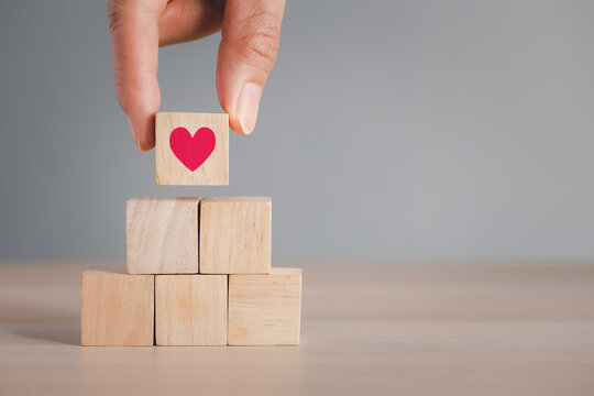 fingers picking top wood cube arranged on wood table