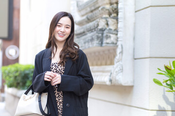 Portrait of young stylish hipster business beautiful Asian woman is walking on the street, wearing cute trendy outfit, turn behind and looking thoughtful in winter lifestyle.