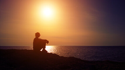Fototapeta na wymiar Silhouette of a woman watching sunset over distant horizon.