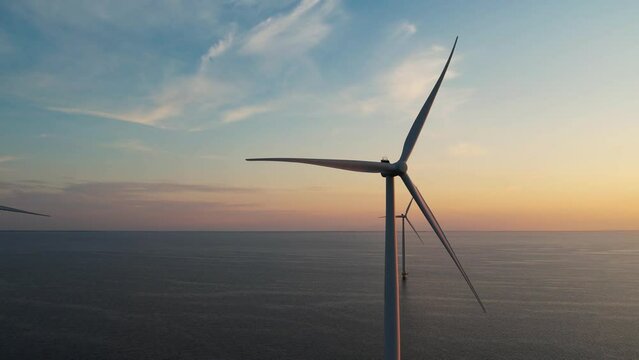 Aerial view of wind turbines at sunset. Working offshore wind farm. Concept: power plant, climate change, sustainable resources, global warming, alternative energy source, renewable energy.