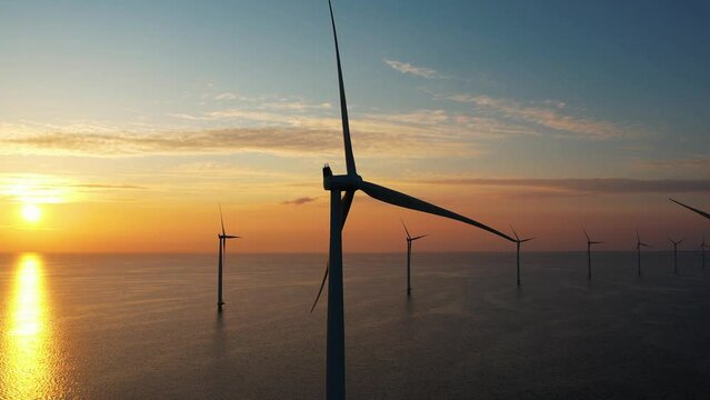 Aerial view of wind turbines at sunset. Working offshore wind farm. Concept: power plant, climate change, sustainable resources, global warming, alternative energy source, renewable energy.