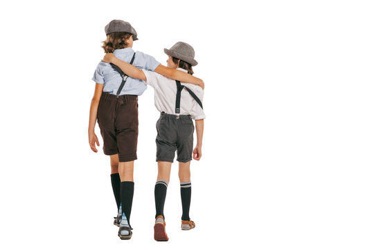 Back view of two school age boys, kids wearing retro clothes isolated over white background. Concept of childhood, vintage summer fashion style