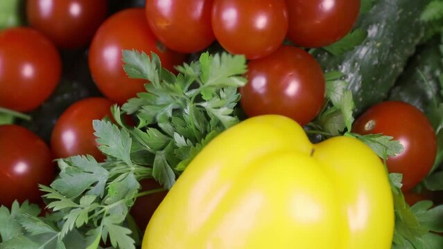 Raw red cherry tomatoes with parsley cucumbers, yellow bell fresh sweet pepper, close-up on a spinning stand