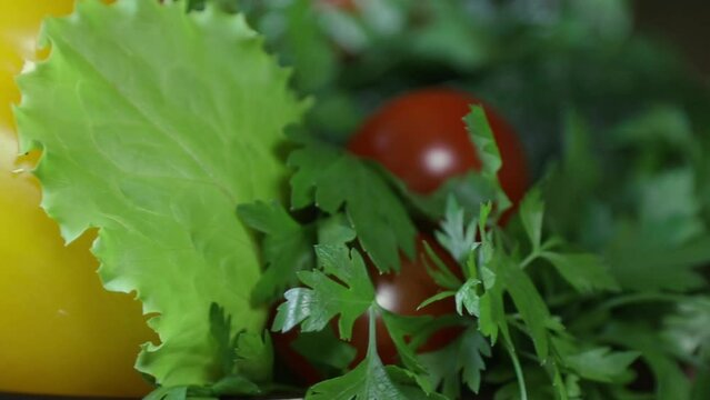Raw red cherry tomatoes with parsley cucumbers, yellow fresh sweet pepper, close-up on a spinning stand