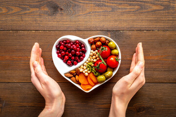 Hands holding heart shaped dish full of healthy diet food