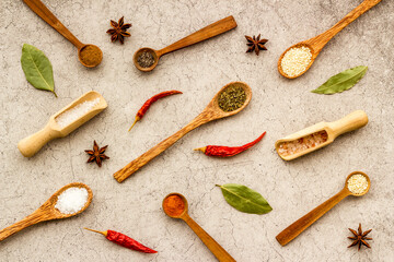 Fototapeta na wymiar Variety of colorful spices and herbs in wooden spoons on kitchen table, top view