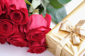 Gift box for Valentine Day tied with golden satin ribbon bow and beautiful roses