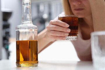 Drunk depressed alcoholic woman drinking whiskey alone at home