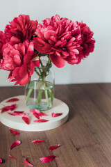 red peonies in a vase on the wooden  table