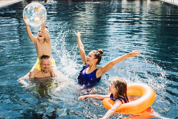 Happy family with two kids having fun in the swimming pool. Summer vacation concept