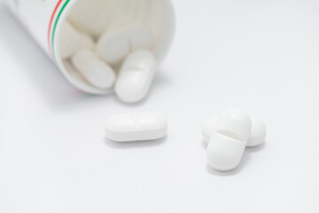 White pills spilling out of drug bottles on white background