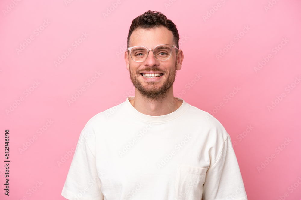 Wall mural young brazilian man isolated on pink background with glasses with happy expression