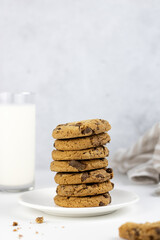 Crispy biscuits with chocolate pieces and a glass of milk on a gray background, copy space.