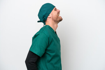 Surgeon Brazilian man in green uniform isolated on white background laughing in lateral position