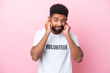 Young volunteer man isolated on pink background frustrated and covering ears