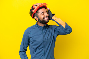 Young cyclist Brazilian man isolated on yellow background smiling a lot