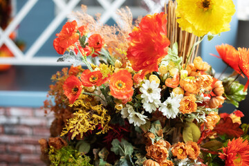 Autumn bouquet of yellow and orange flowers. Beautiful floral arrangement with fall orange and red flowers and berries, closeup. Cozy Interior fall decor with Autumn composition plants at home. 