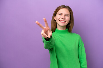 Young English woman isolated on purple background smiling and showing victory sign