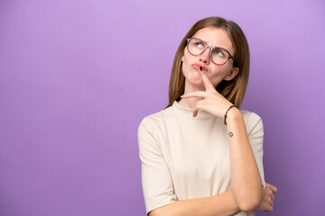 Young English woman isolated on purple background having doubts while looking up